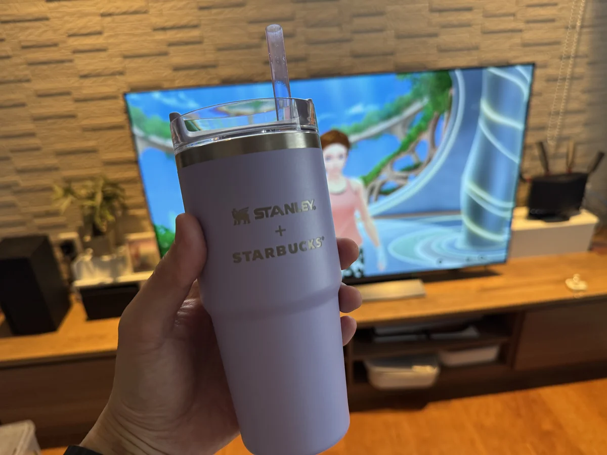 フィットボクシングを再生中のテレビの前で、ストロー付きタンブラーを手に持っている様子