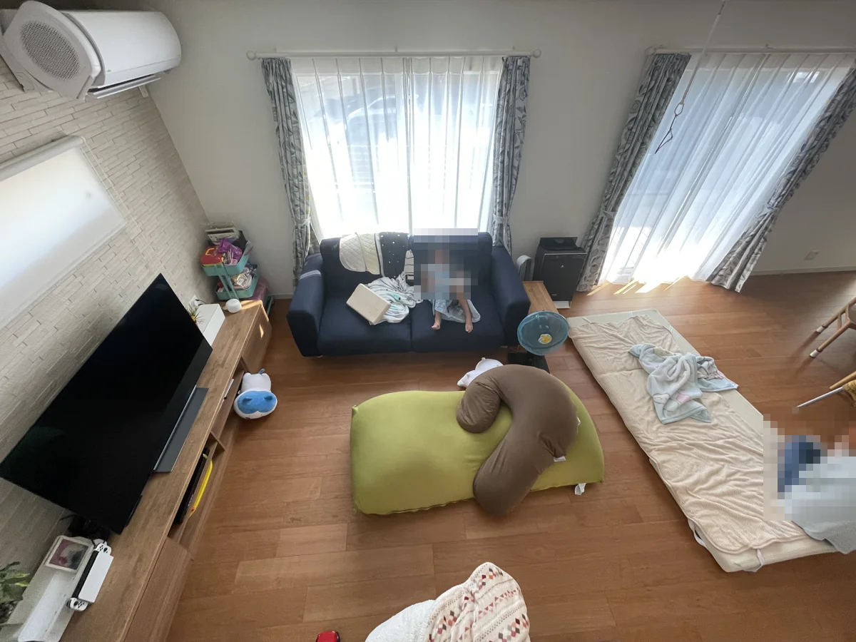 吹き抜けの上から見下ろしたリビング。Yogibo Maxとサポート、ソファ、床のマットが並ぶ(人物はモザイク処理済み)