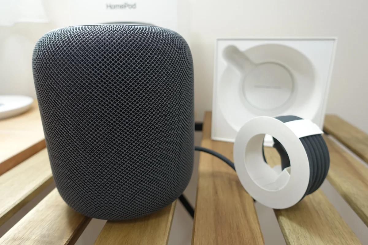木の台の上に置いたHomePod(初代)。横に箱の内側の梱包と、巻かれた電源ケーブルがある
