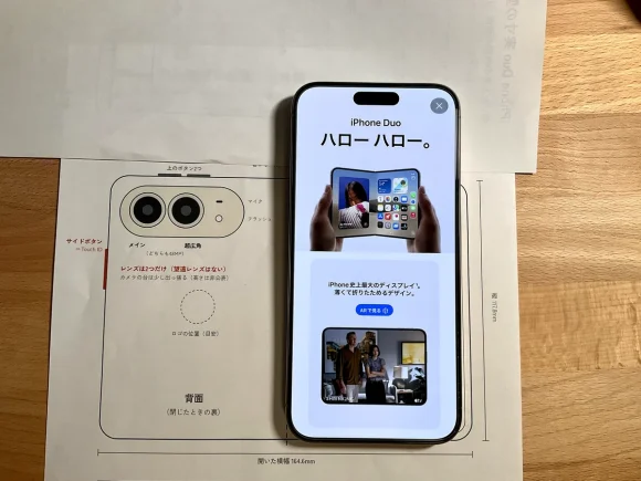 iPhone Duoの実寸の型紙（背面側）の上に、iPhone 15 Pro Maxを折り目に合わせて置いた写真