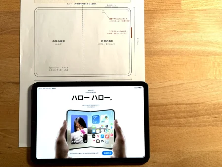 開いたiPhone Duoの実寸の型紙の下に、iPad mini 6を置いて大きさを比べた写真