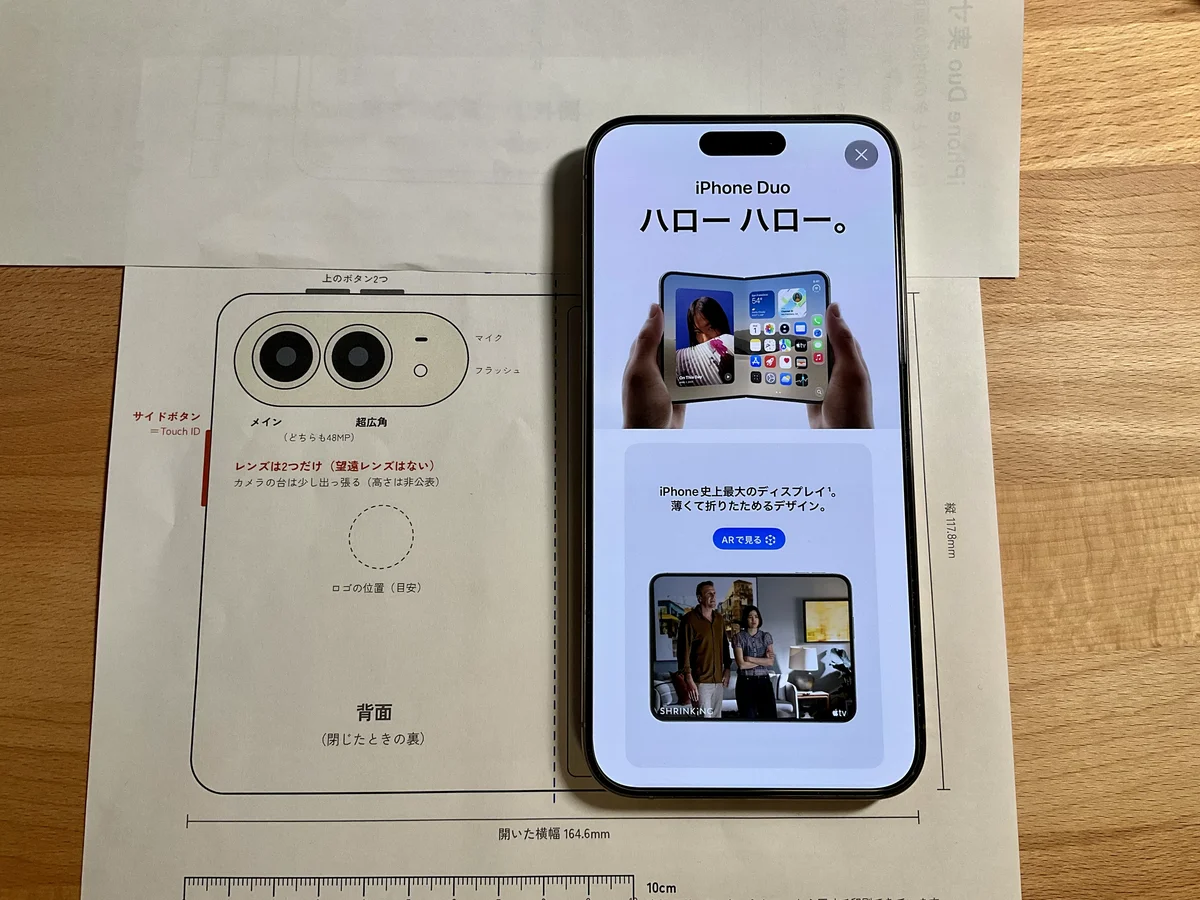 iPhone Duoの実寸の型紙(背面側)の右の縁に、iPhone 15 Pro Maxの右の縁をそろえて置いた写真。15 Pro Maxは型紙より上にはみ出している